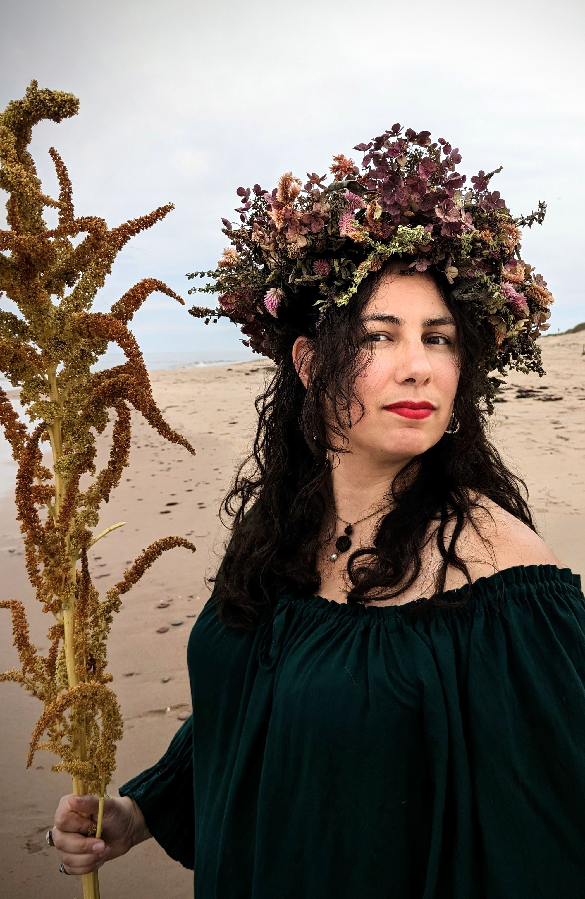 Another entry in the flower-wreath beach portraits: I'm dressed in a flowy dark green shirt falling slightly off one shoulder while holding a stalk of amaranth like a staff and wearing a very elaborate crown of herbs and flowers (celosia, hydrangea, basil, oregano and mint) over my long wavy dark hair, with ocean in the background.