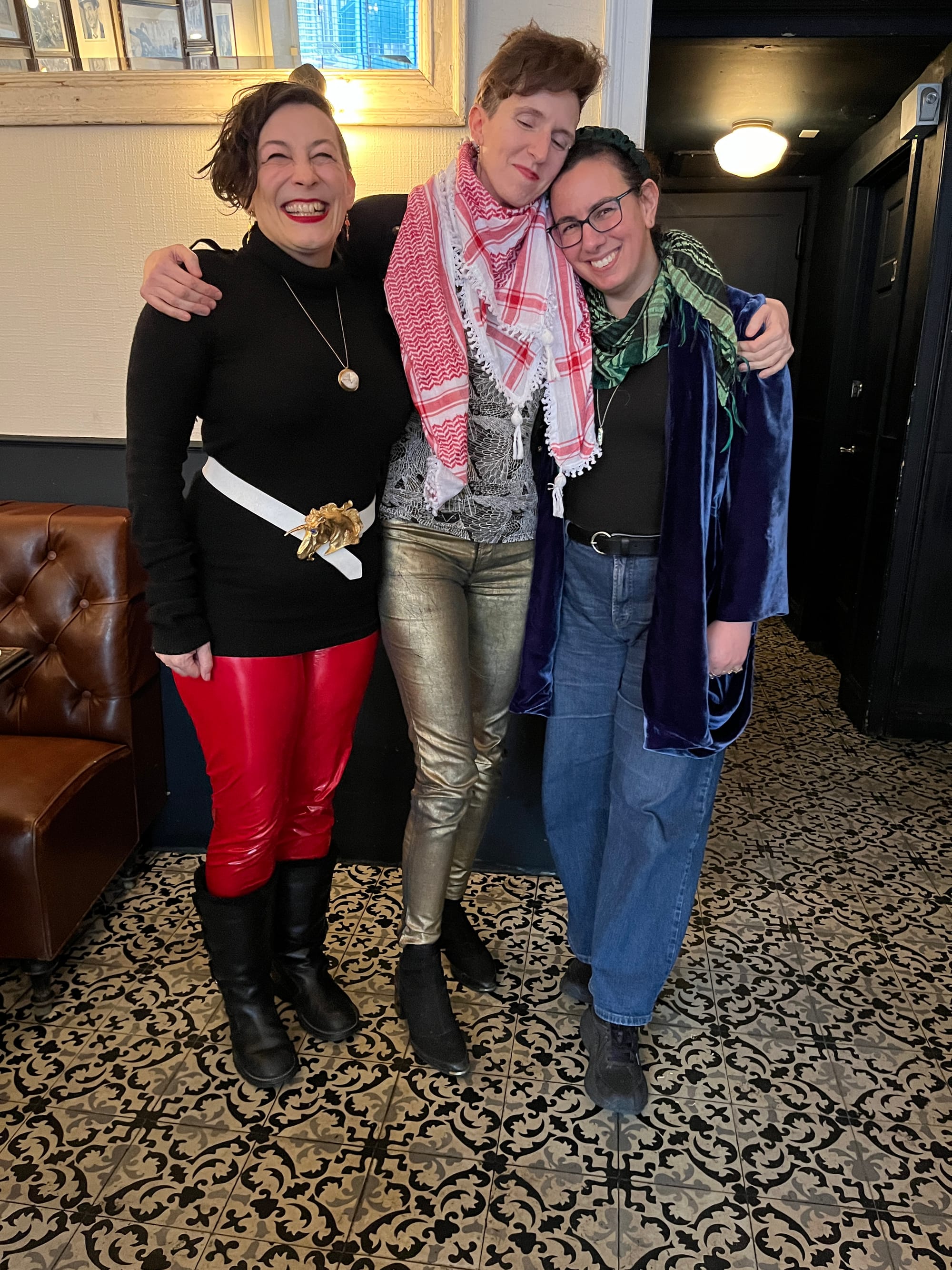 A photo of Maria Dahvana Headley, Bo Bolander, and myself in a diner called Walter's with a superbly tiled foliate floor. Maria and Bo are extremely fashion forward; Maria's wearing bright red leatherish trousers, black boots, and a black tunic long-sleeved top, waist defined with a white belt clasped with a huge gold unicorn head buckle; Bo's wearing shiny slim-fitting gold trousers, a black and white tshirt with a wing pattern on it under a red and white keffiyeh; and I'm wearing a black and green keffiyeh over a blue silk velvet jacket, black tank top, black belt and wide-leg bluejeans.