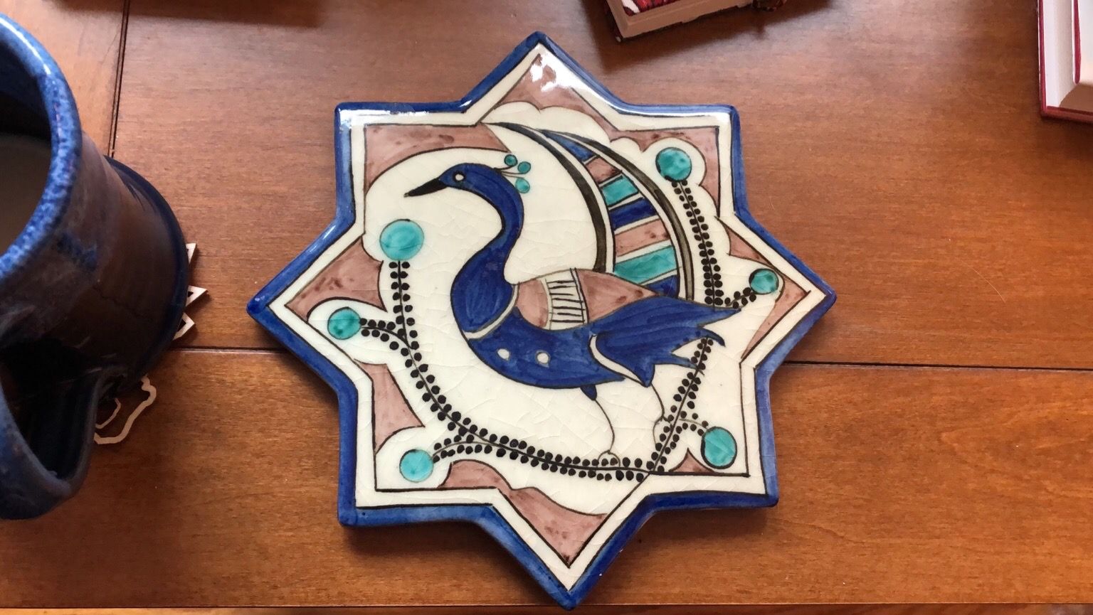 A glazed octogonal ceramic tile depicting a stylized peacock.