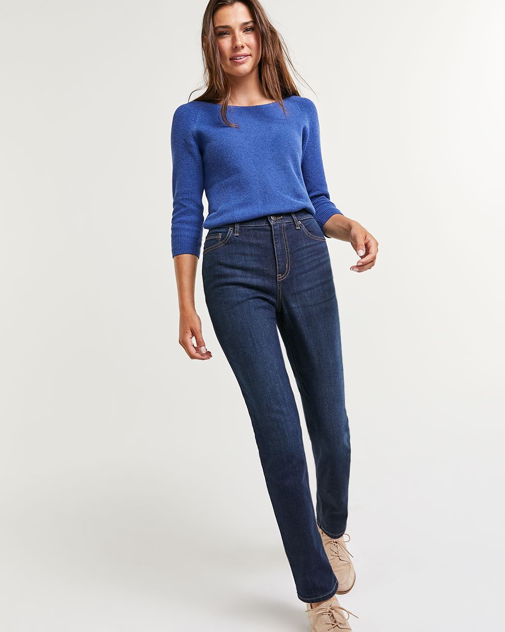 A stock image from Reitmans of a tall thin woman wearing high-waisted dark-blue jeans with a lighter blue 3/4 length top.
